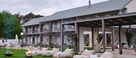 Un hotel con mesas al aire libre, fogones y un patio cubierto.