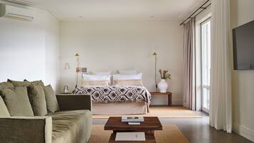 A modern bedroom with a bed, a sofa, a coffee table, and a TV.