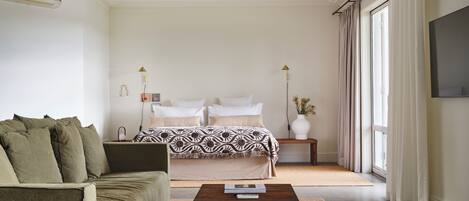 A modern bedroom with a bed, a sofa, a coffee table, and a TV.
