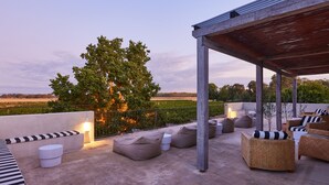 Un patio en la azotea con mobiliario exterior, una pérgola y vistas a un viñedo.