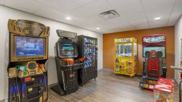 Enjoy classic arcade games in this lively indoor space featuring a 'Big Buck Hunter' slot machine, 'NASCAR' racing game, and 'Taxi' claw machine.