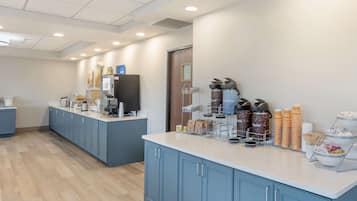A modern kitchen area with a long counter, blue cabinets, and various kitchen appliances.