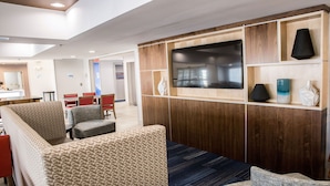 A modern hotel lobby with a seating area, a flat-screen TV mounted on a wooden panel, and a reception desk in the background. - Holiday Inn Express Columbus-Dublin by IHG (Dublin)