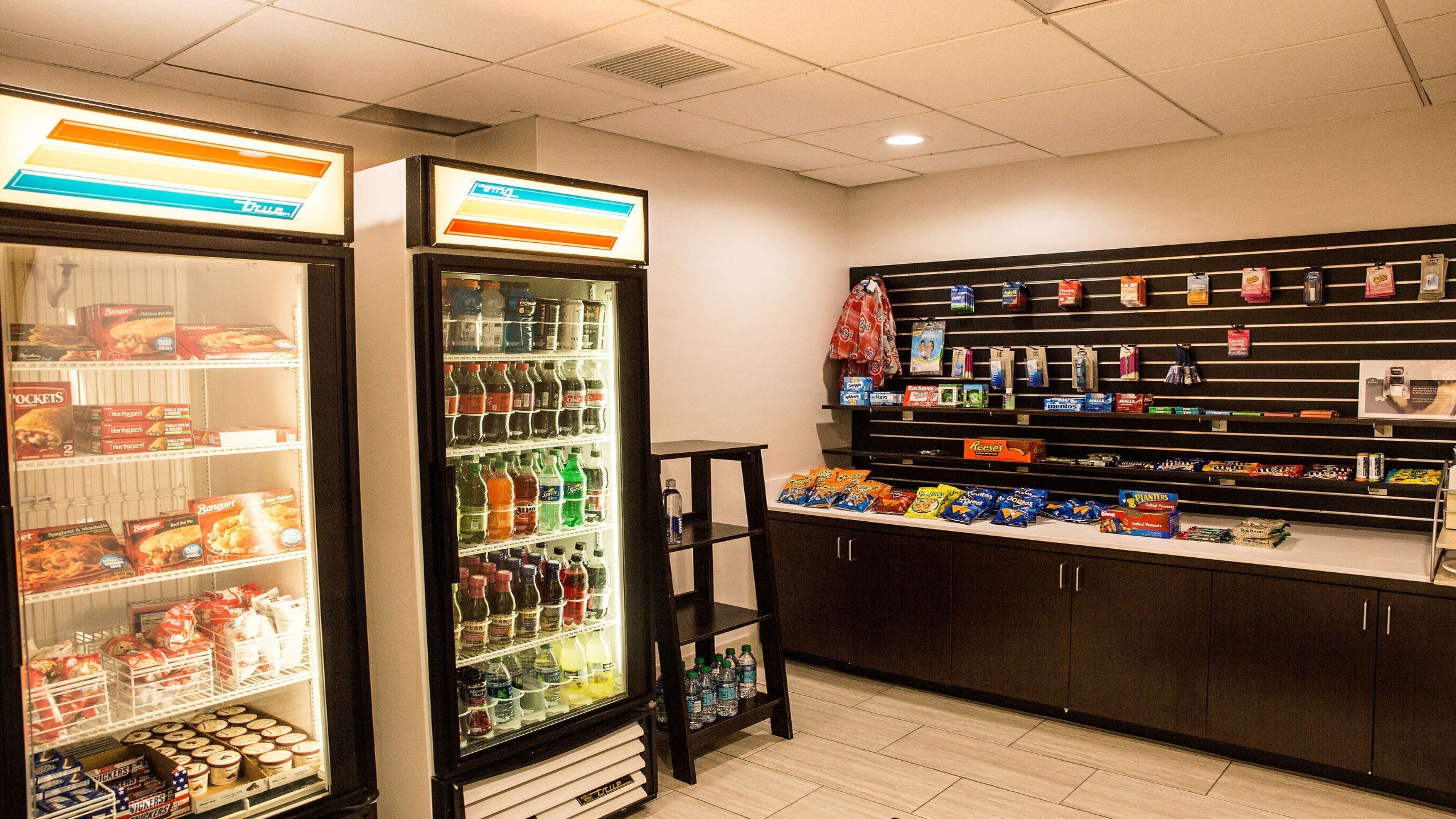 A convenience store with refrigerated sections on the left and shelves stocked with snacks and beverages on the right.