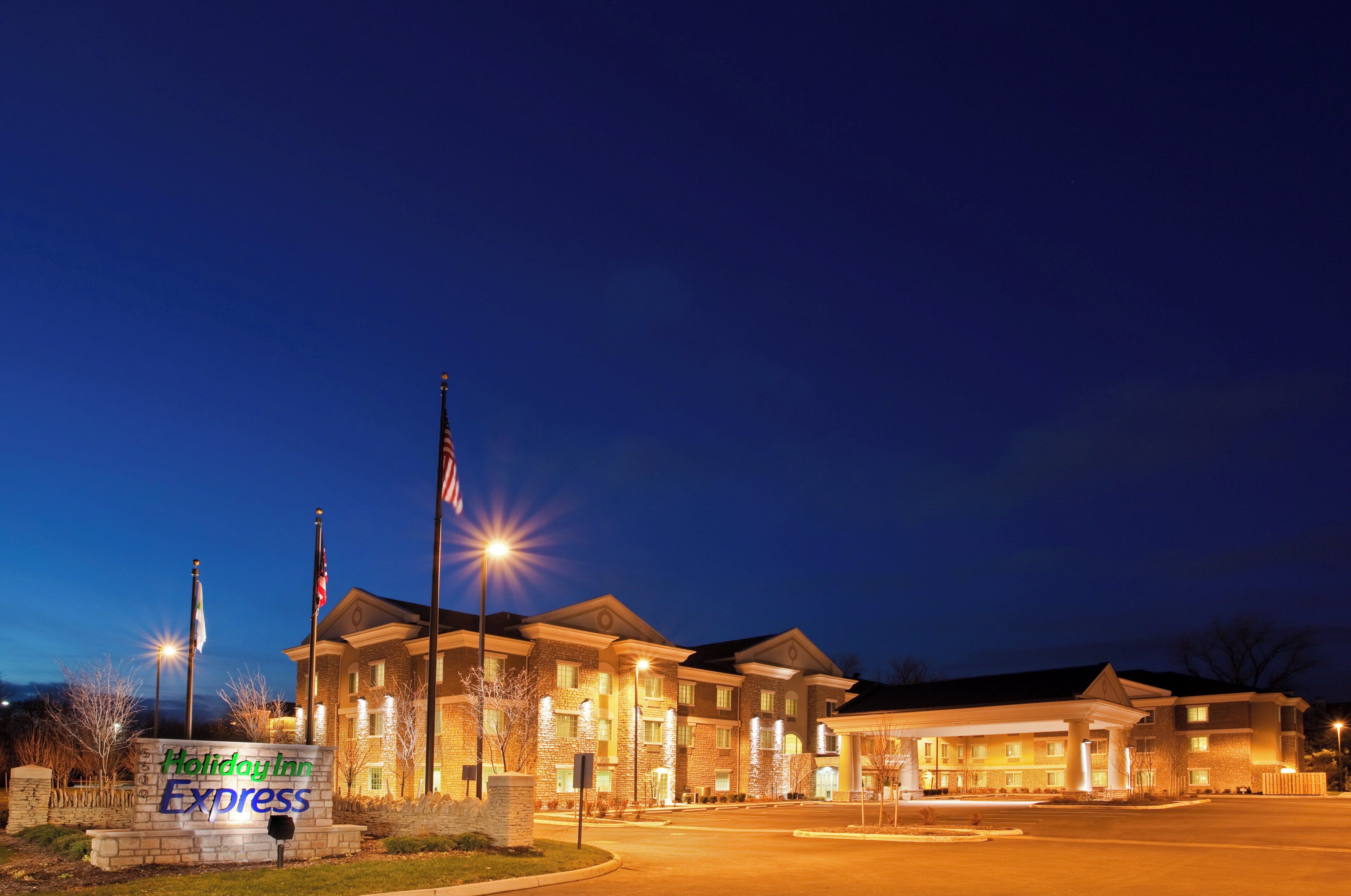 A Holiday Inn Express hotel with a stone facade, multiple entry points, and a well-lit parking area.
