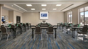 A conference room with tables and chairs, a projector screen, and a large window.