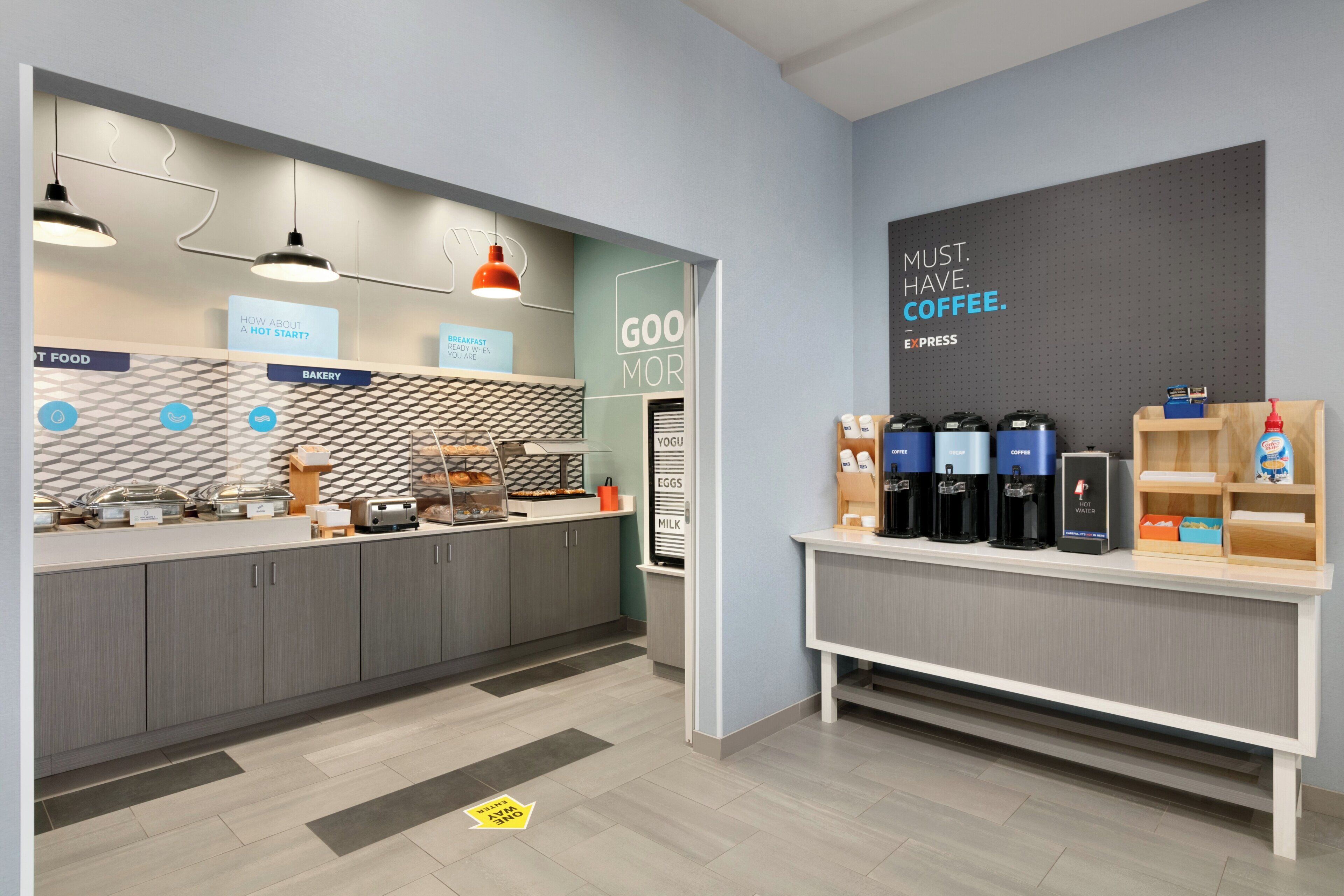 A modern cafe with a breakfast bar, coffee machines, and a sign reading 'GOOD MORNING.'