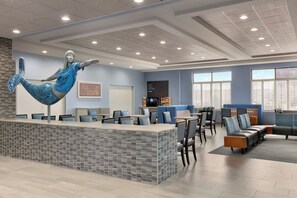 A modern lobby with a reception desk, seating area, and a large decorative sculpture. - Holiday Inn Express Hotel & Suites Norfolk Airport by IHG (Norfolk)