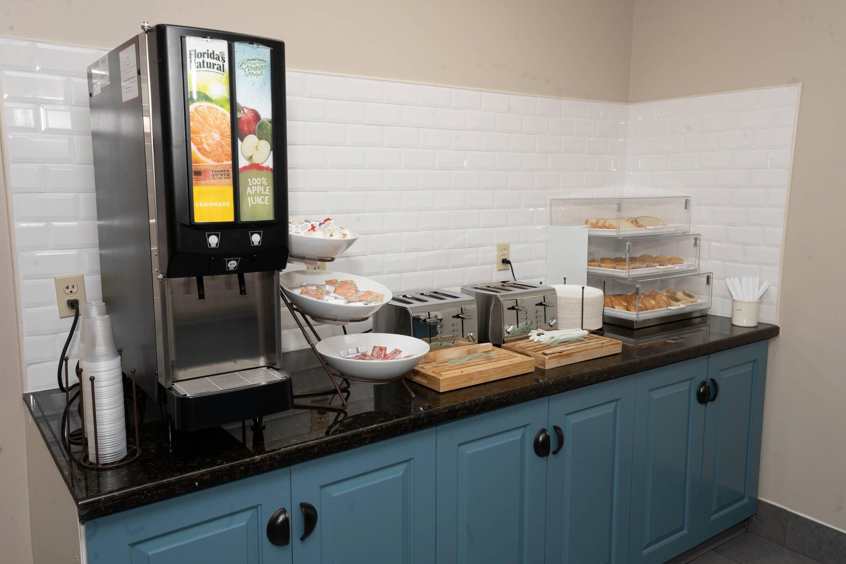 A breakfast bar with a coffee machine, bowls, trays, and a fruit juice dispenser.