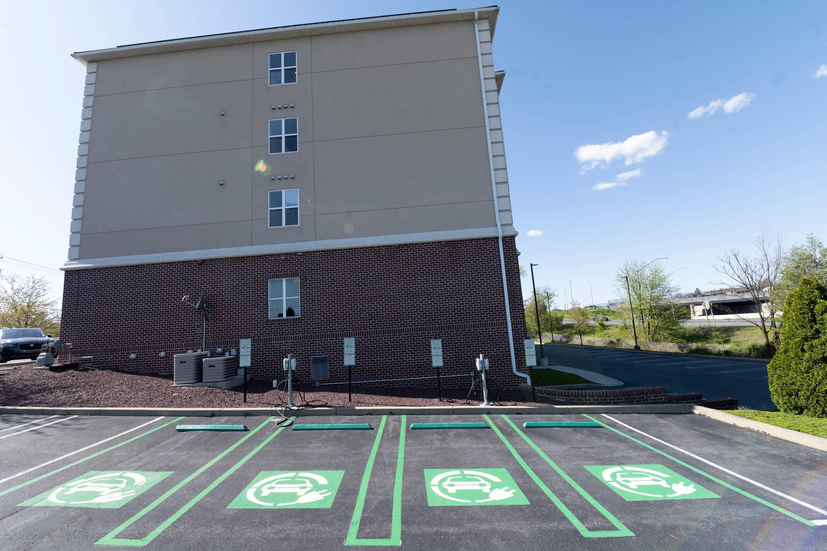 A parking lot with electric vehicle charging stations and a multi-story building with a brick facade.