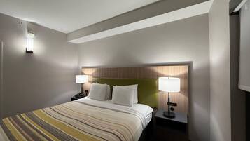A hotel room with a bed, two bedside tables, a headboard, and wall-mounted lamps.