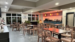 A restaurant with wooden tables and chairs, a counter with a menu, and a view through large windows. - Country Inn & Suites by Radisson, Harrisburg - Hershey West, PA (Harrisburg)