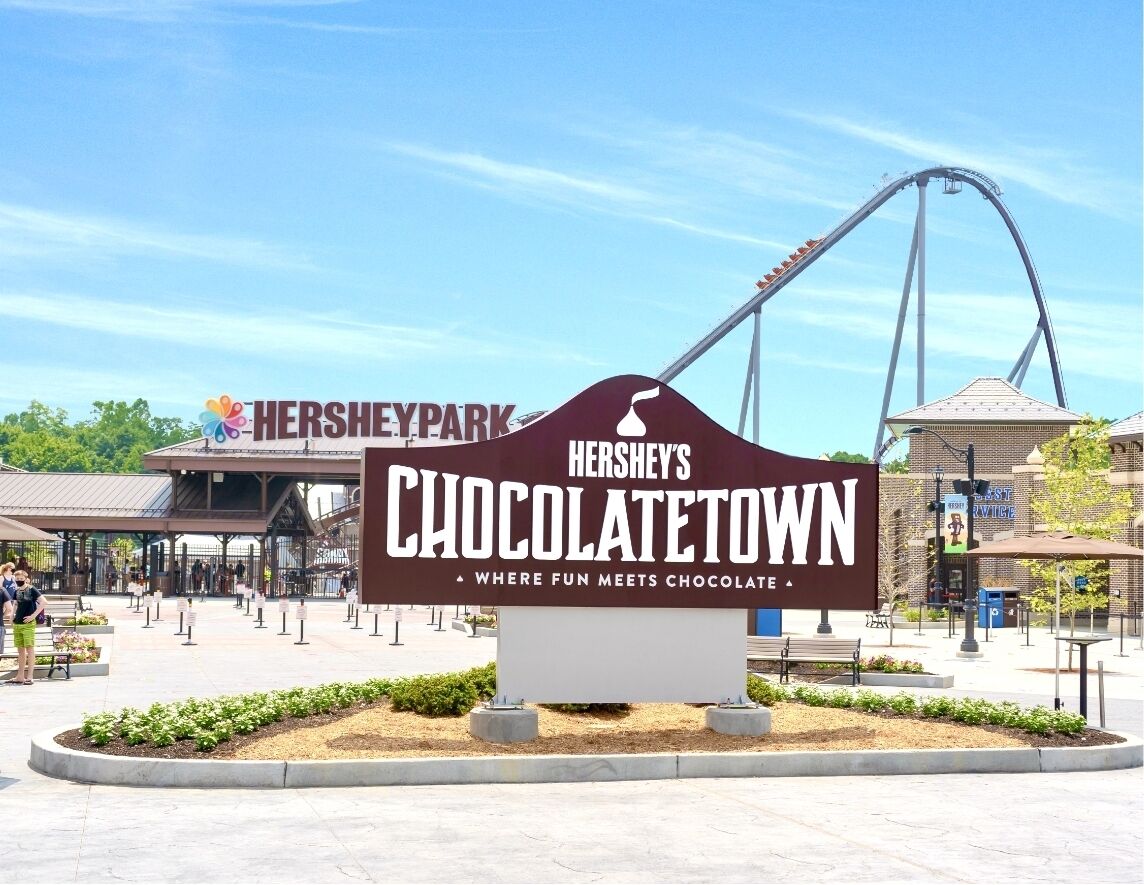 Señal de Chocolate Town de Hershey's con una montaña rusa al fondo.