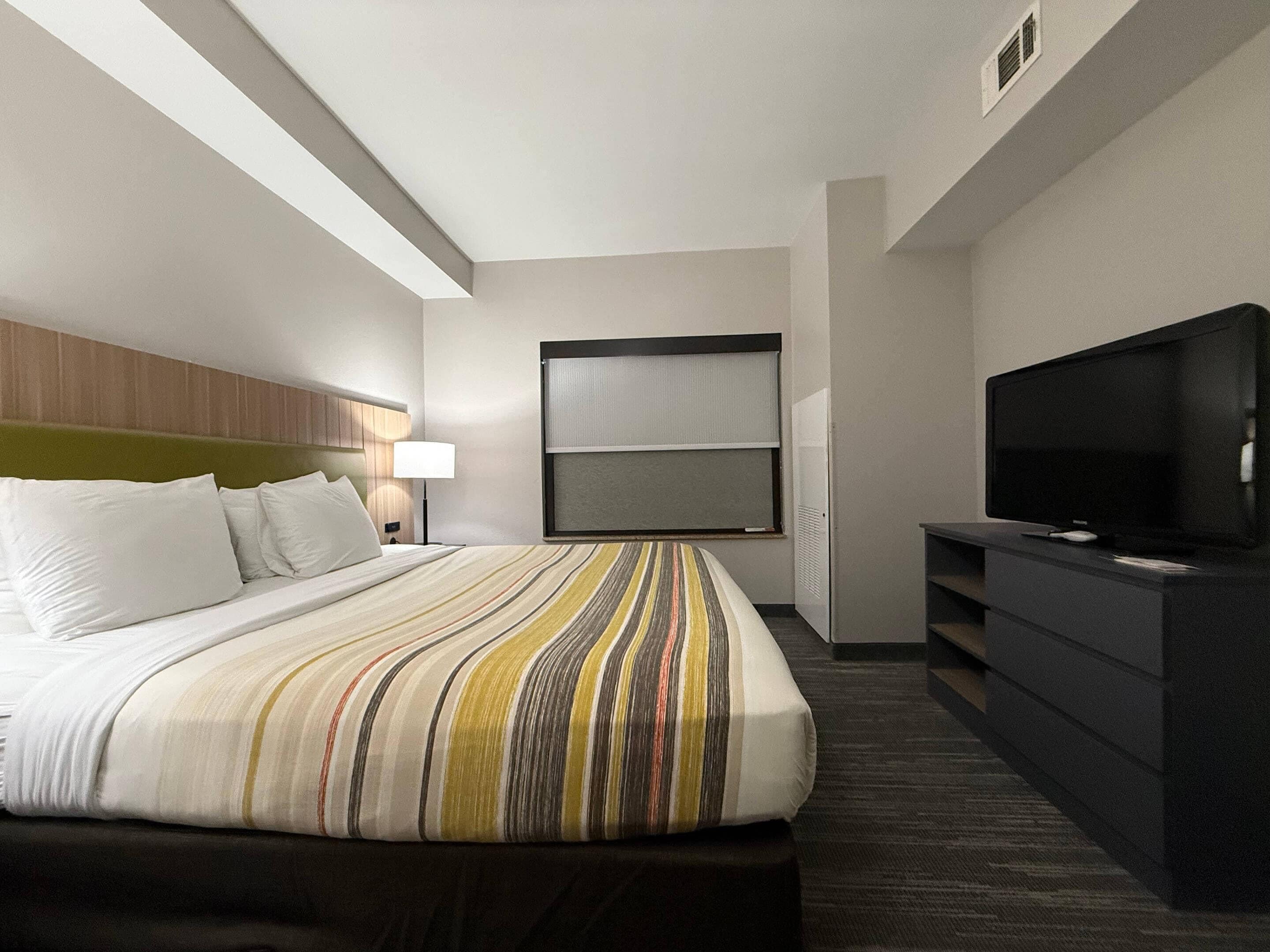 Ein Hotelzimmer mit Bett, Fernseher, Schreibtisch und Fenster.