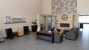 A modern lobby with a seating area, a reception desk, a wall-mounted clock, and a fireplace. - Country Inn & Suites by Radisson, Harrisburg - Hershey West, PA (Harrisburg)