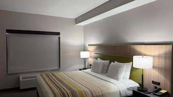A hotel room with a bed, two bedside lamps, a telephone, and a window with blinds.