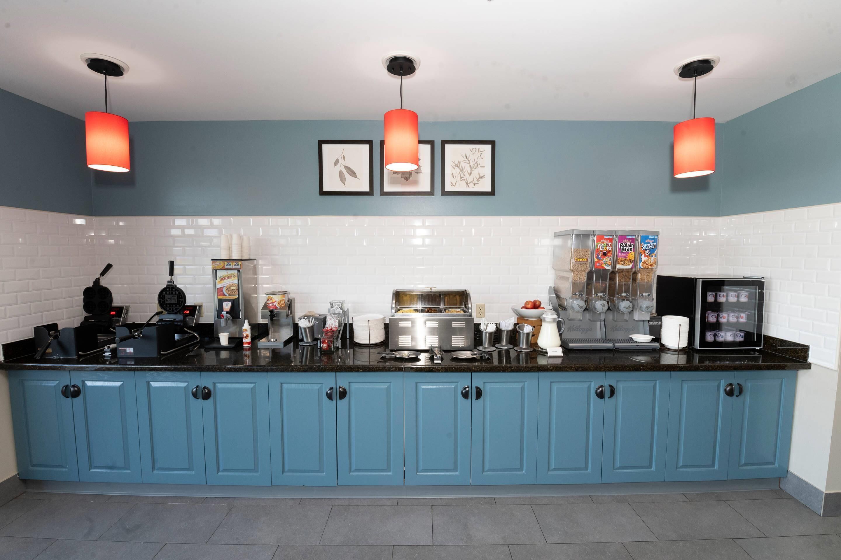 A kitchen with blue cabinets, a black countertop, and three pendant lights.