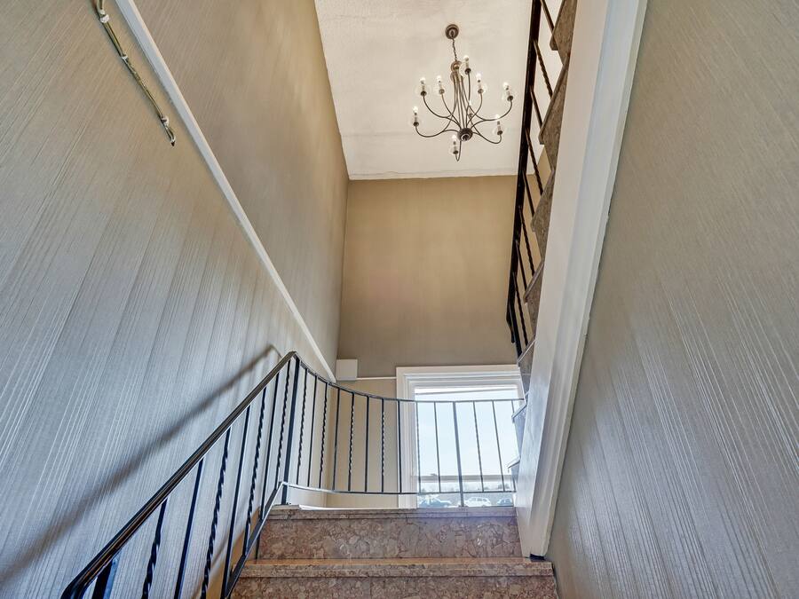 Eine Treppe mit einem Chandelier, einer weißen Tür oben und Blick ins Freie.