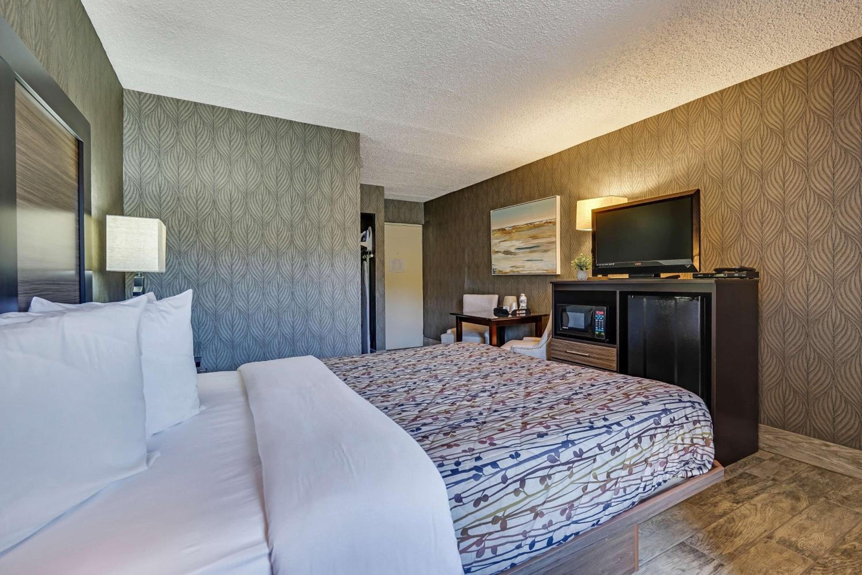 Ett hotellrum med en stor säng, en tv, ett skrivbord och en sittgrupp.