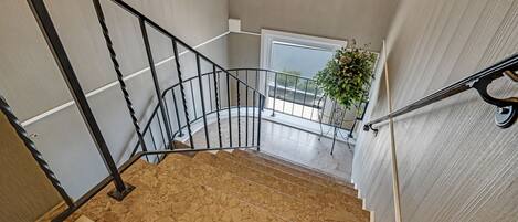 A staircase with a black metal railing, a potted plant, and a view of the outdoors through a window.