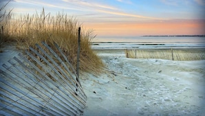 Une plage avec des dunes de sable et une clôture en bois.