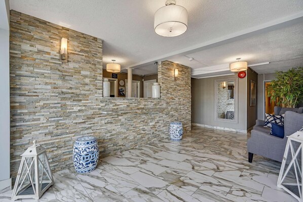 A spacious lobby with a stone wall, marble flooring, and modern lighting fixtures. - Blue Creek Inn (Waretown)