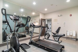 A fitness center with cardio machines, a mirrored wall, and a door leading to another area. - Sleep Inn and Suites at Kennesaw State University (Kennesaw)
