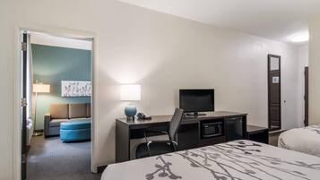 Una habitación de hotel con una cama, un escritorio con computadora, una silla, un televisor y una pequeña cocina.