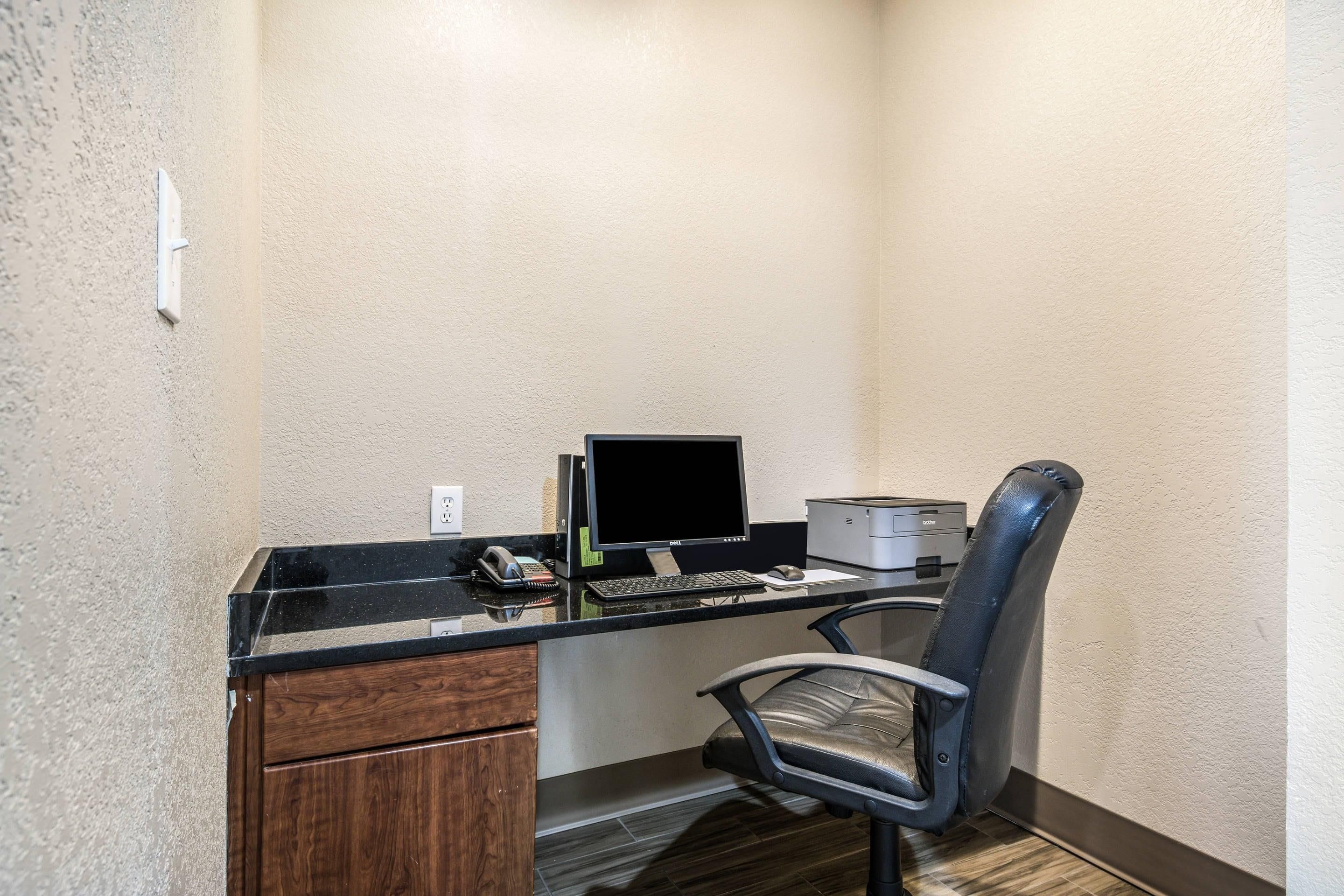 A small office space with a desk, computer, printer, and a chair.
