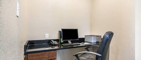 A small office space with a desk, computer, printer, and a chair.