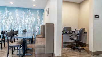A conference room with a long table, multiple chairs, a computer desk with a monitor, and a wall with a tree pattern.