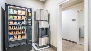 Máquina expendedora con refrigerios y dispensador de agua en un pasillo.