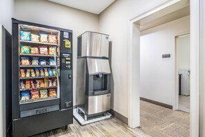 A vending machine stocked with snacks and a water dispenser in a hallway. - Sleep Inn and Suites at Kennesaw State University (Kennesaw)