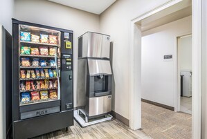 Máquina de vendas automática com lanches e bebedouros em um corredor.