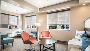 A modern hotel lobby with seating areas, large windows, and a central table. - Sleep Inn and Suites at Kennesaw State University (Kennesaw)