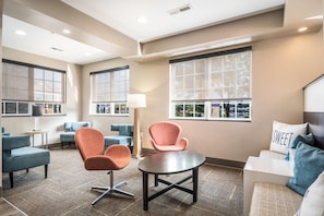 Une chambre d’hôtel dotée d’un coin salon, d’une table ronde et de grandes fenêtres offrant une vue dégagée.