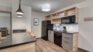 Una cocina moderna con encimera negra, electrodomésticos de acero inoxidable y armarios de madera.