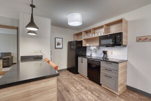 Una cocina moderna con encimera negra, electrodomésticos de acero inoxidable y armarios de madera.