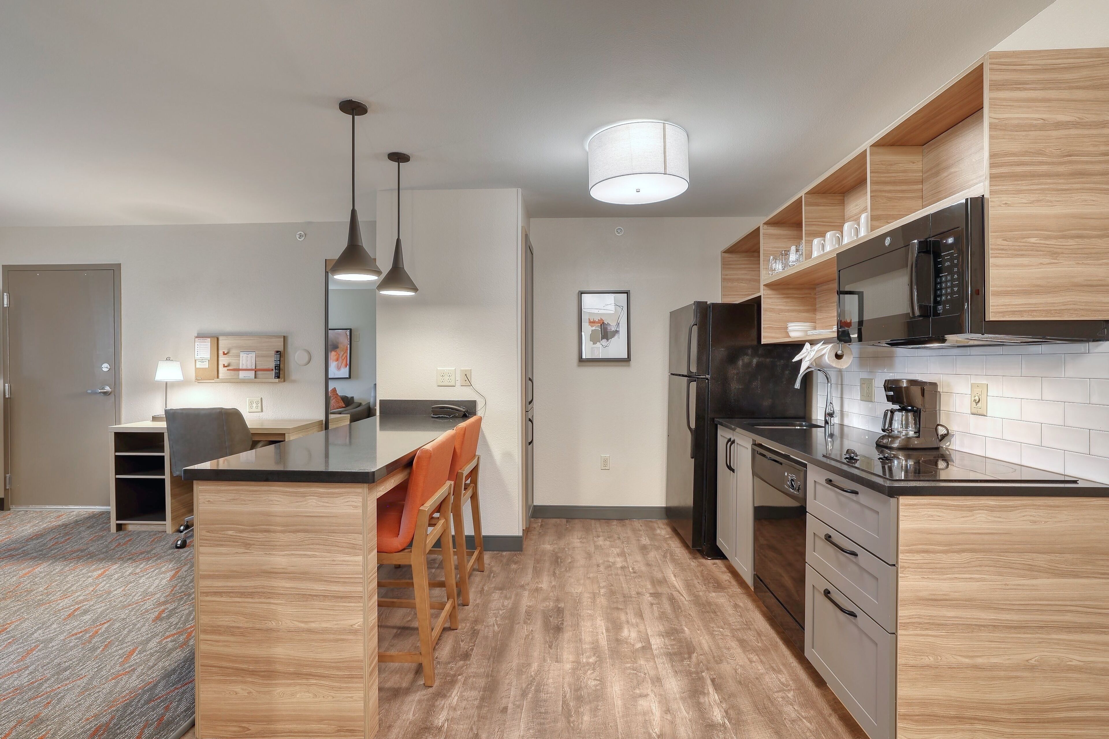 Een moderne keuken met houten kastjes, een roestvrijstalen koelkast en een inbouwmagnetron.