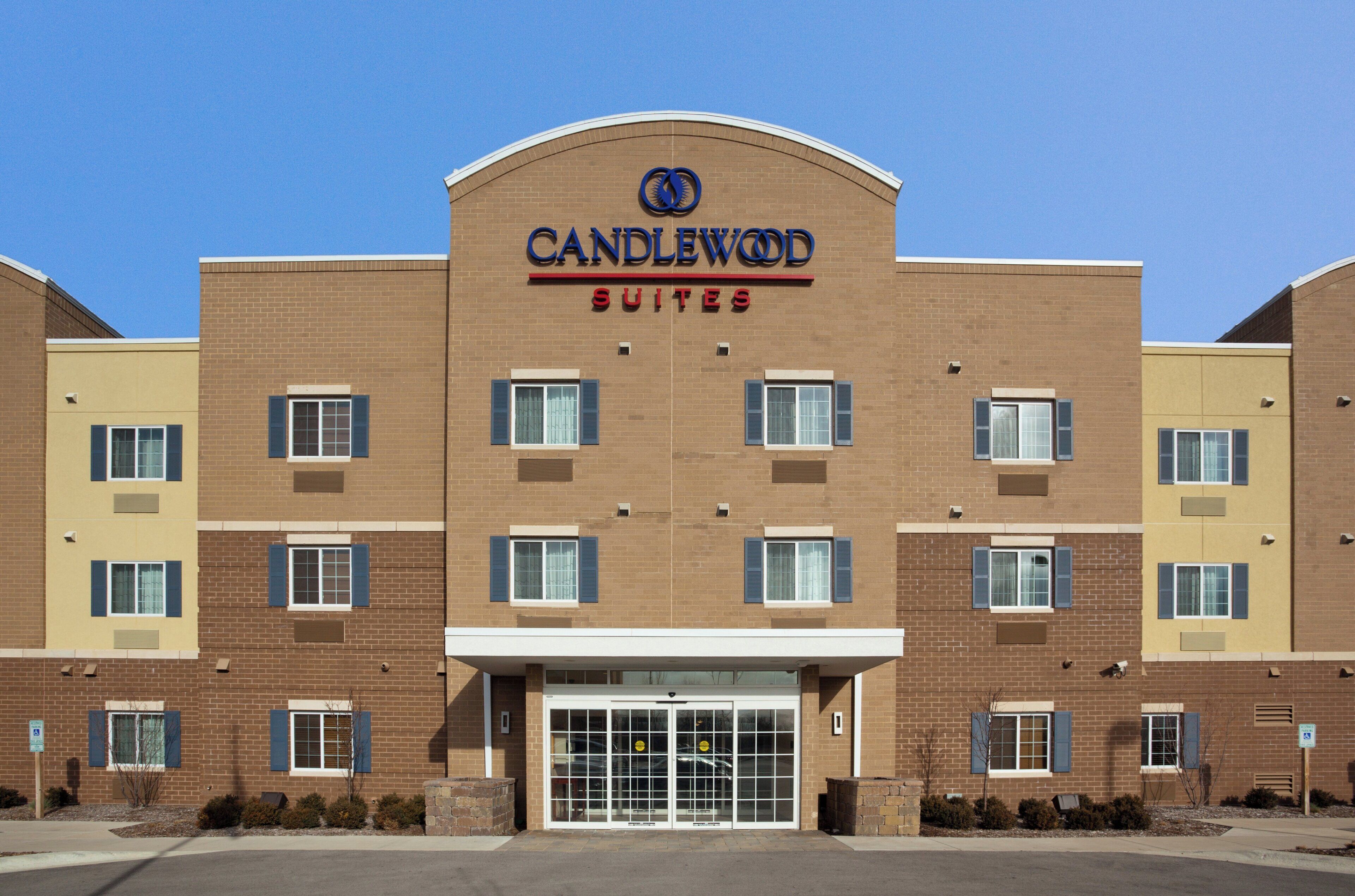 En byggnad i tegel med en skylt som visar texten ”CANDLEWOOD SUITES”, vilket indikerar att det är ett hotell.