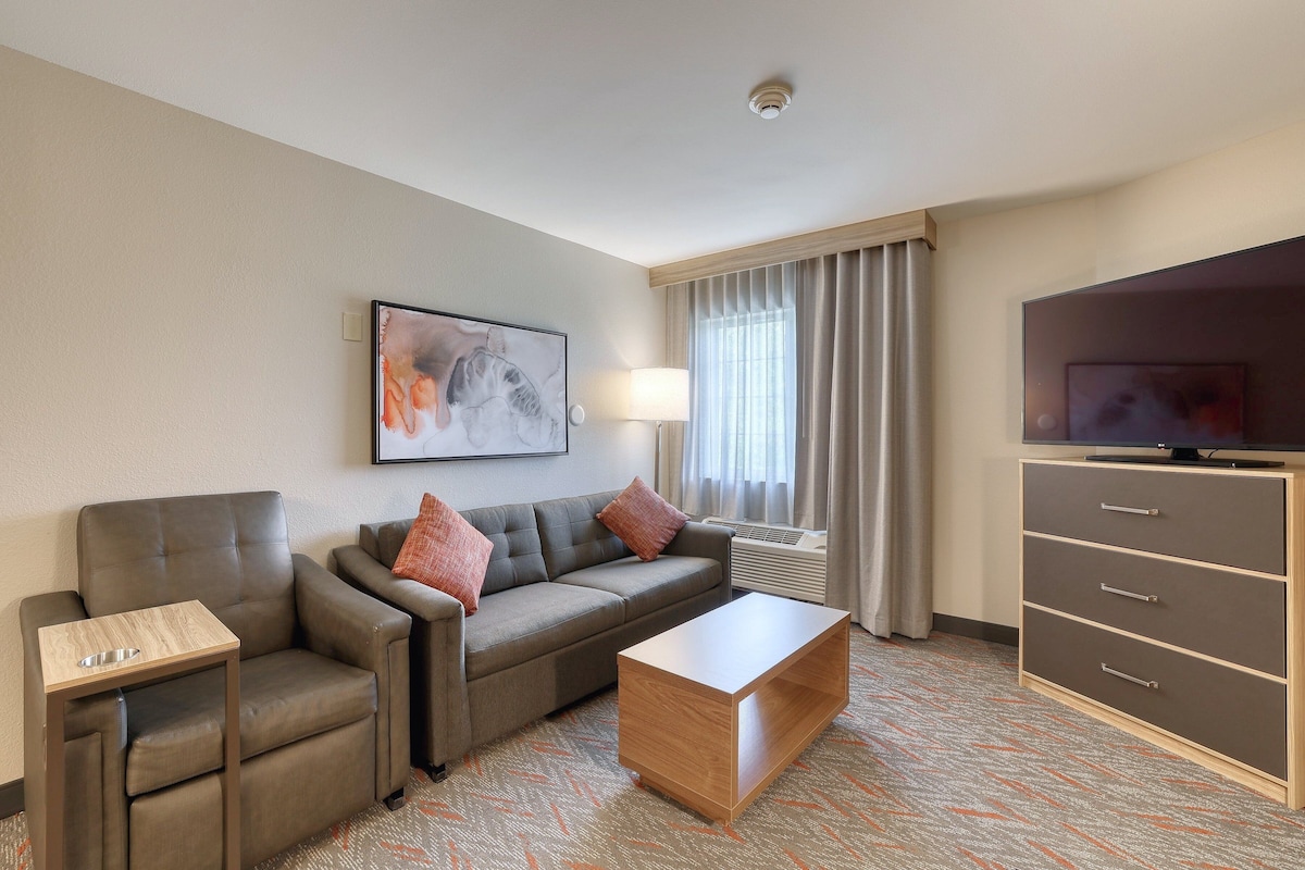 A hotel room with a sofa, a coffee table, a TV, and a cabinet.
