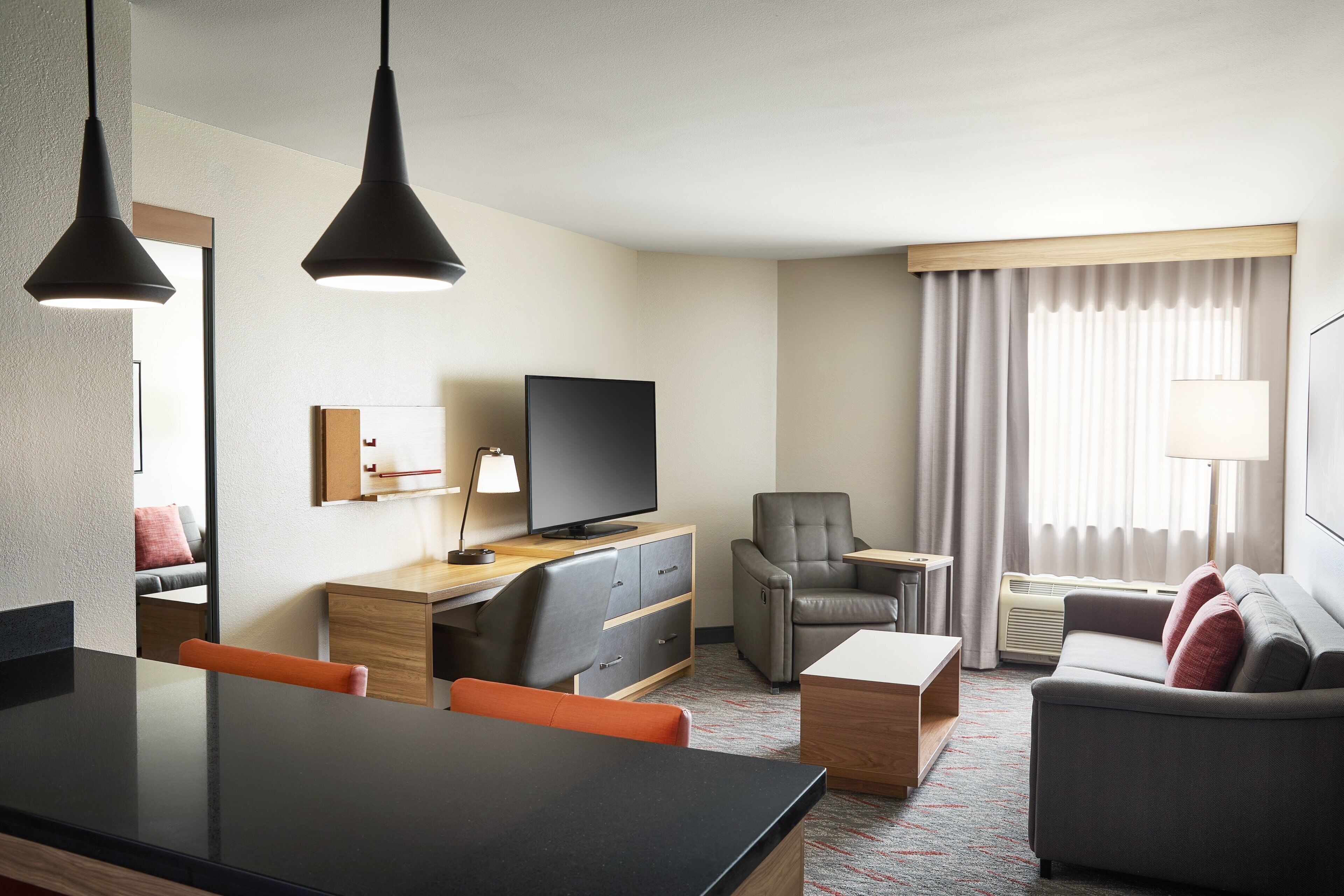 Habitació d'hotel moderna amb zona de menjador, sofà, televisió i escriptori.