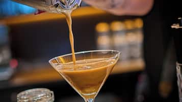 A bartender pouring a drink into a martini glass.