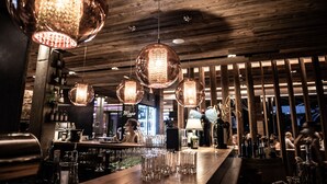Zona de bar con techo de madera y lámparas esféricas colgantes.