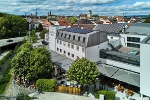 Un hotel moderno con jardín en la azotea, una zona de estar al aire libre cubierta y vistas del pueblo circundante.