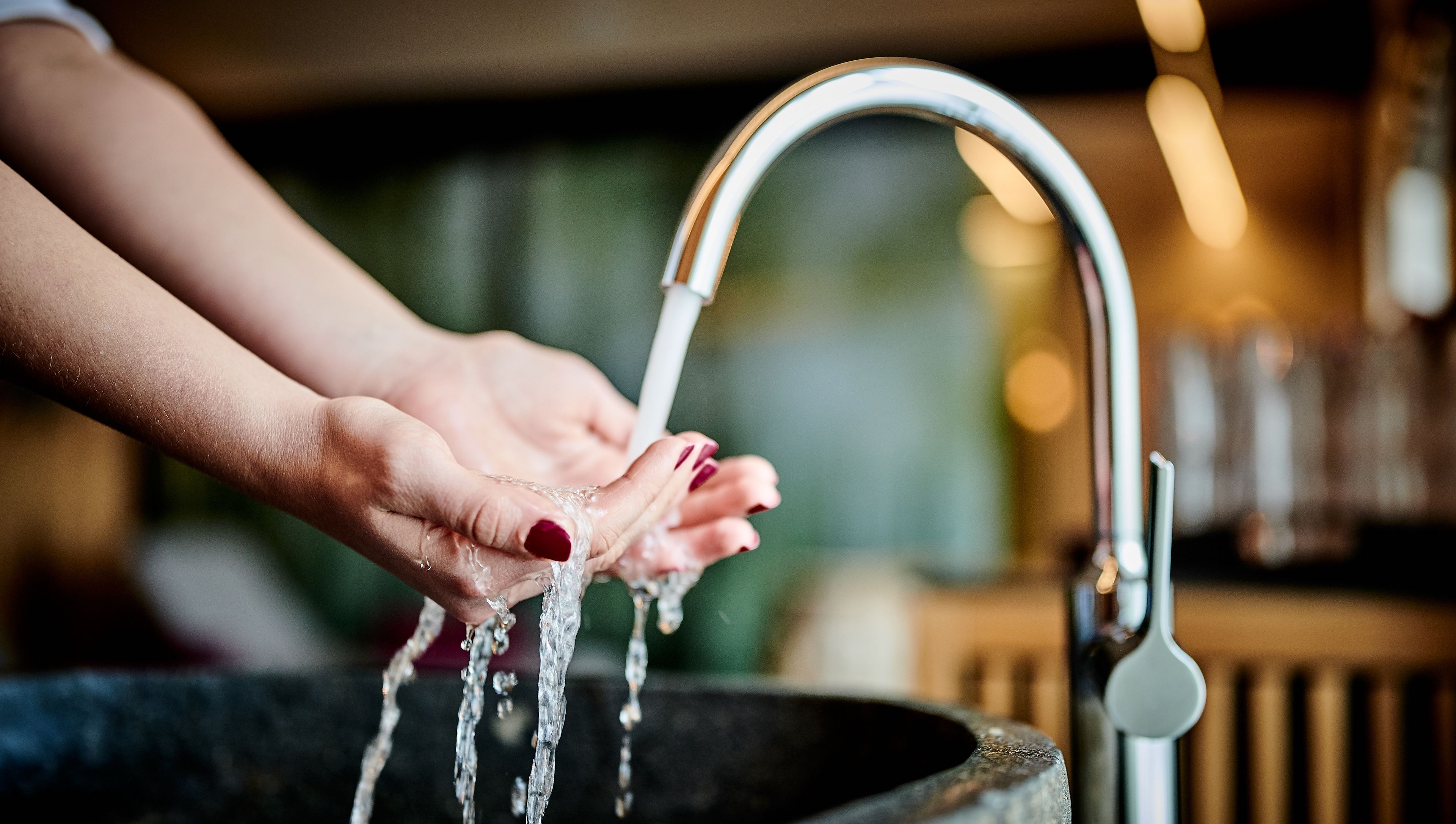 Una mano bajo un grifo abierto, con agua fluyendo.