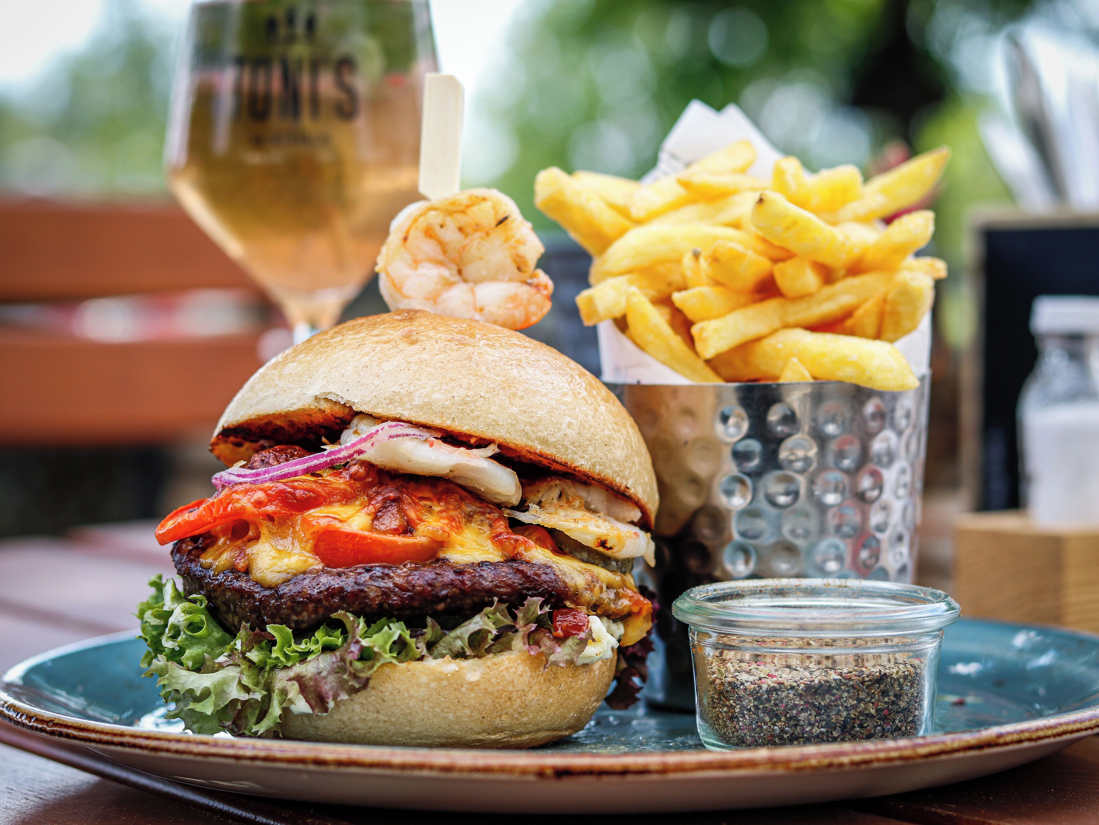 Un hamburger accompagné de frites et d’une boisson, le tout posé sur une table.