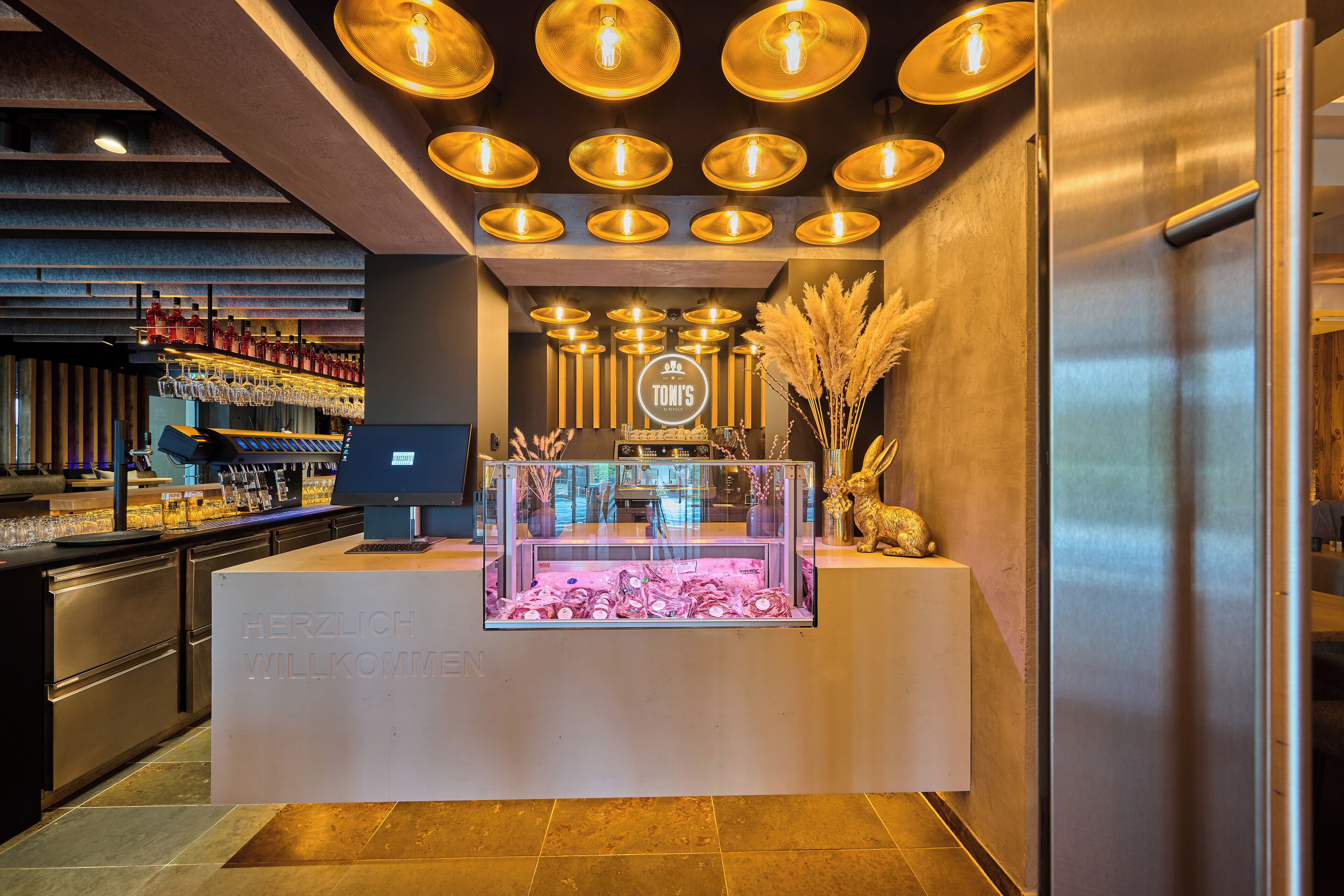 A bar area with a counter, shelves with bottles, and a display case.