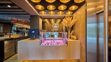 A bar area with a counter, shelves with bottles, and a display case.