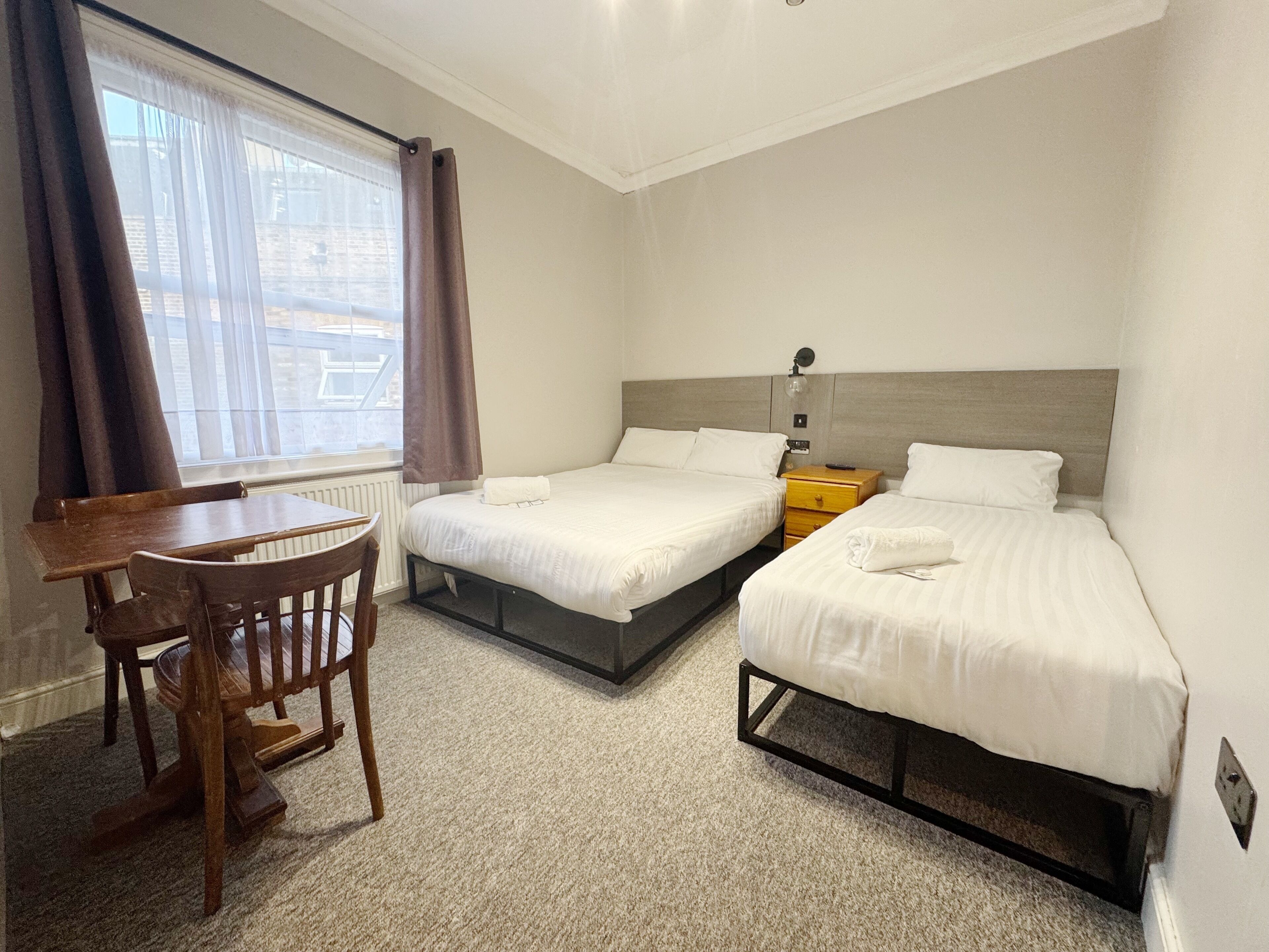 A hotel room with two beds, a desk, and a chair.